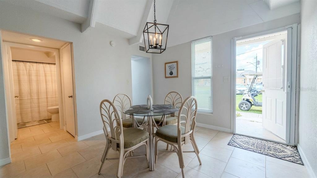 A dining area with a glass table, four chairs, a chandelier, and an open door — 1011 CLUB CIRCLE, LAKE WALES, FL