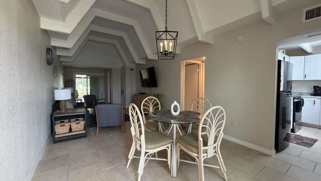 A dining area with a glass table and wicker chairs sits beneath a vaulted ceiling — 1011 CLUB CIRCLE, LAKE WALES, FL