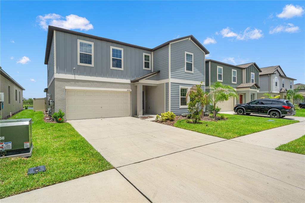 A two-story house with gray siding, a two-car garage, and a concrete driveway — 22313 PLEASANT MORNING DRIVE, LAND O LAKES, FL