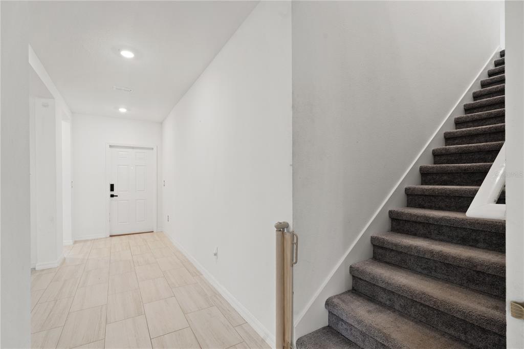 A tiled entryway leads to a carpeted staircase with a wooden safety gate — 22313 PLEASANT MORNING DRIVE, LAND O LAKES, FL