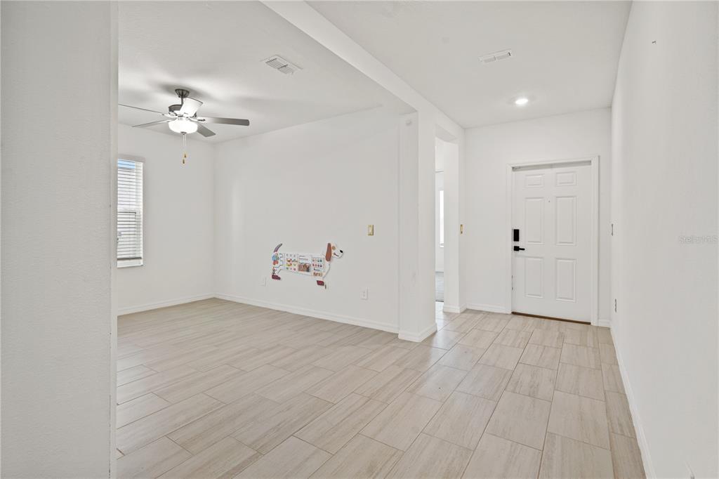 An interior view shows a room with light wood-look tile flooring and a white front door — 22313 PLEASANT MORNING DRIVE, LAND O LAKES, FL