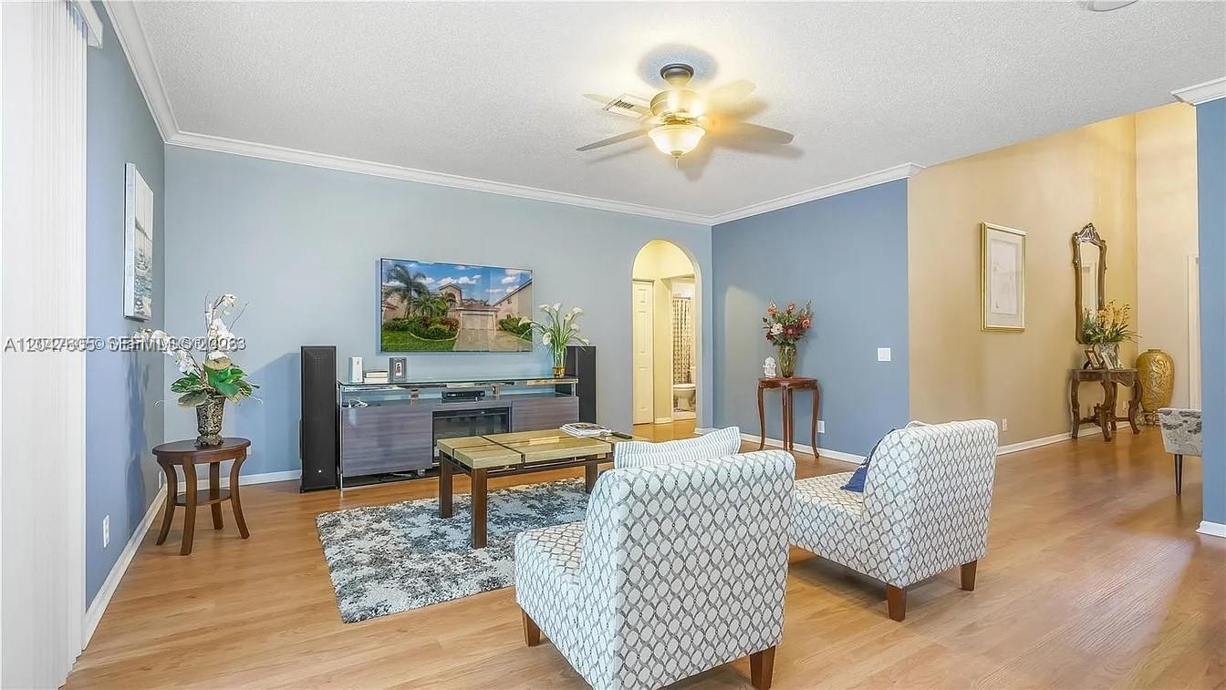 A living room features light blue walls, wood flooring, a ceiling fan, and two armchairs — 1714 Royal Grove Way, Weston FL 33327, WESTON, FL