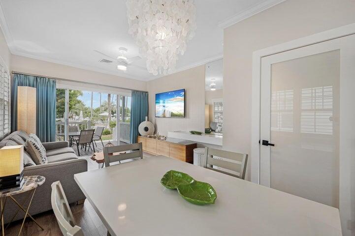 A dining area with a white table and chandelier opens to a living room and patio — 5092 Sunset Village Drive, FL 33050, FL