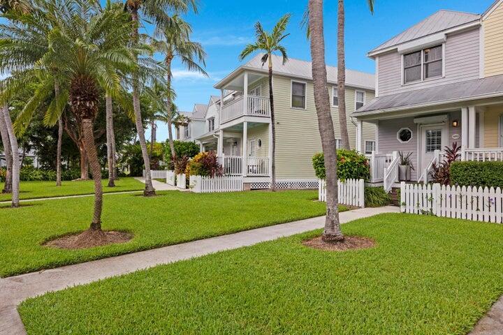 A row of pastel-colored houses with white picket fences and palm trees on a lawn — 5092 Sunset Village Drive, FL 33050, FL