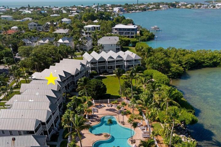 An aerial view shows a multi-unit residential complex with metal roofs beside a swimming pool — 5092 Sunset Village Drive, FL 33050, FL