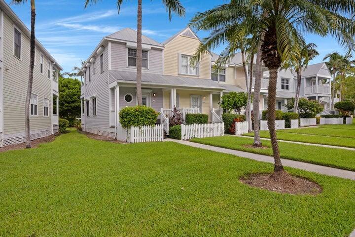 A row of multi-story houses with light-colored siding and white picket fences on a lawn — 5092 Sunset Village Drive, FL 33050, FL