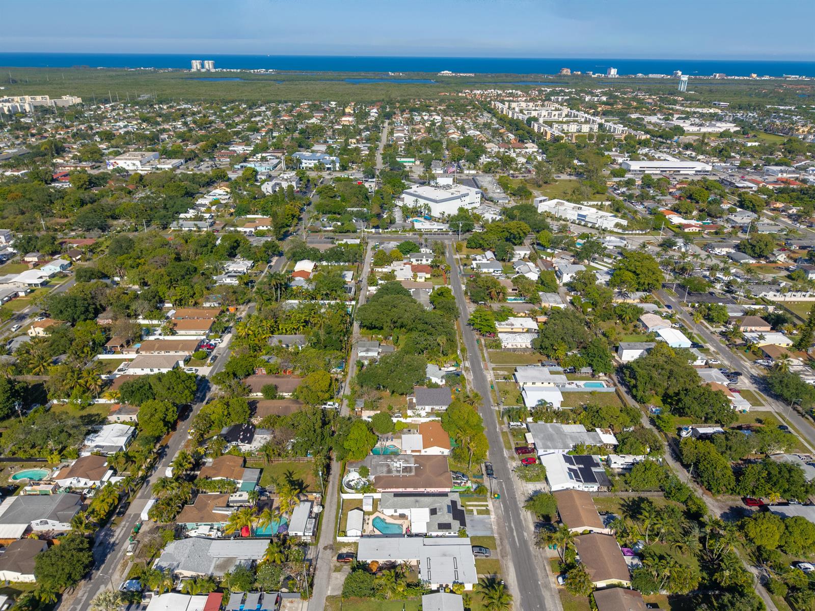 An aerial view shows a residential neighborhood with houses, trees, and distant coastal buildings — 262 SW 8th Street, Dania Beach FL 33004, DANIA BEACH, FL