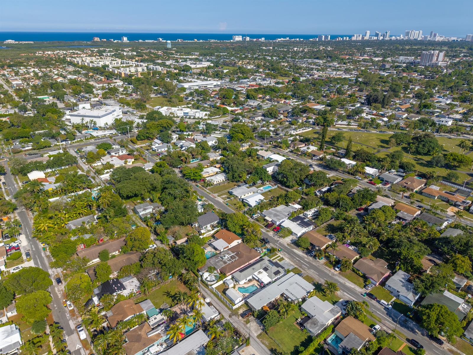 An aerial view of a suburban neighborhood with houses, trees, and a distant coastline — 262 SW 8th Street, Dania Beach FL 33004, DANIA BEACH, FL