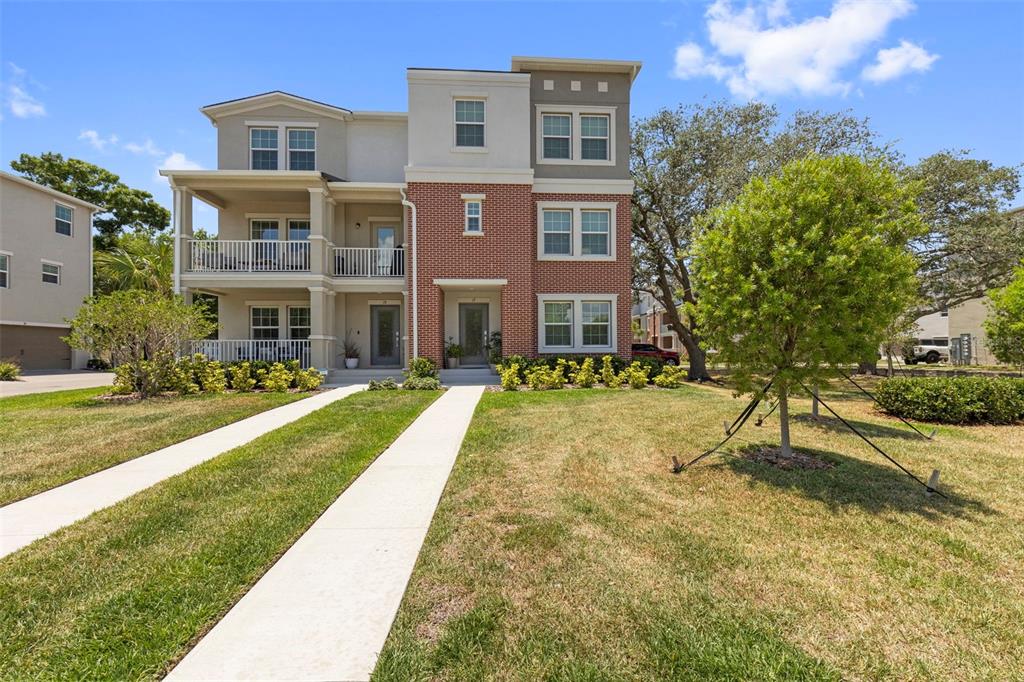 A three-story residential building features a brick facade, white balconies, and a concrete driveway — 4511 S MANHATTAN AVENUE UNIT 17, TAMPA, FL