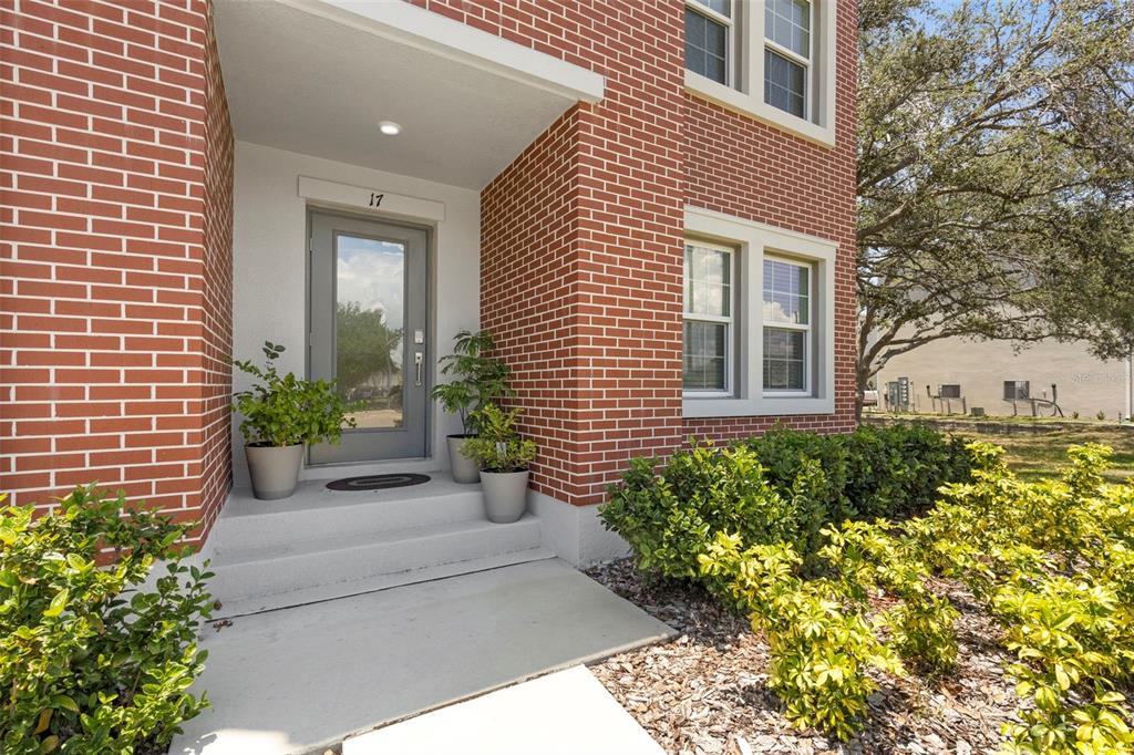 A brick house exterior features a gray front door with the number 17 above it — 4511 S MANHATTAN AVENUE UNIT 17, TAMPA, FL