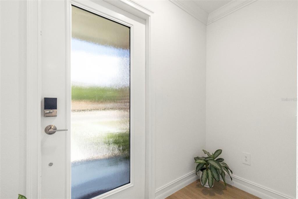 A white front door with a frosted glass panel sits in a bright entryway — 4511 S MANHATTAN AVENUE UNIT 17, TAMPA, FL