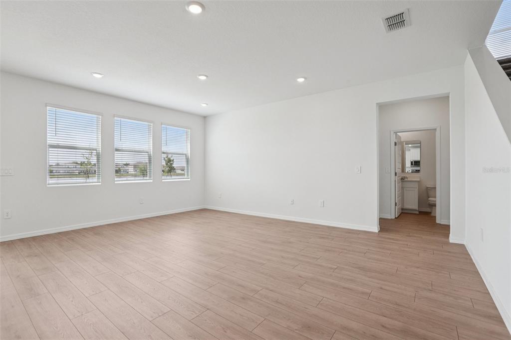 An empty room with light wood-look flooring, white walls, recessed lighting, and three windows — 5392 CLOUDBERRY, LAKELAND, FL