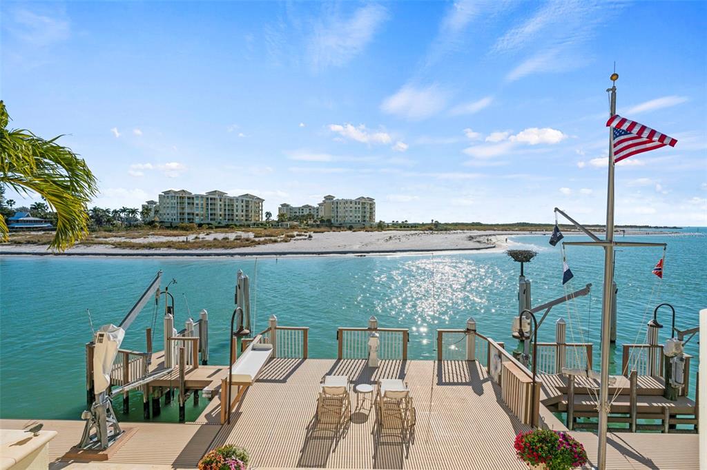 A wooden deck with lounge chairs overlooks a bay with a distant sandy beach — 964 MONTE CRISTO BOULEVARD, TIERRA VERDE, FL