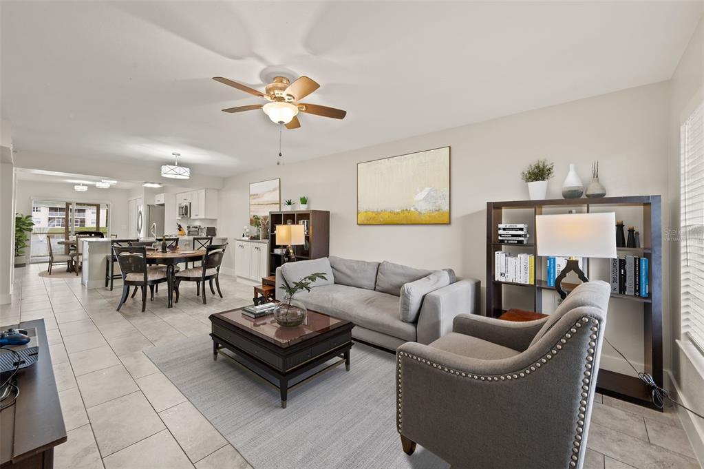 A living room with tile floors, a gray sofa, an armchair, and an open kitchen — 4910 COUGAR COURT N UNIT 103, NAPLES, FL