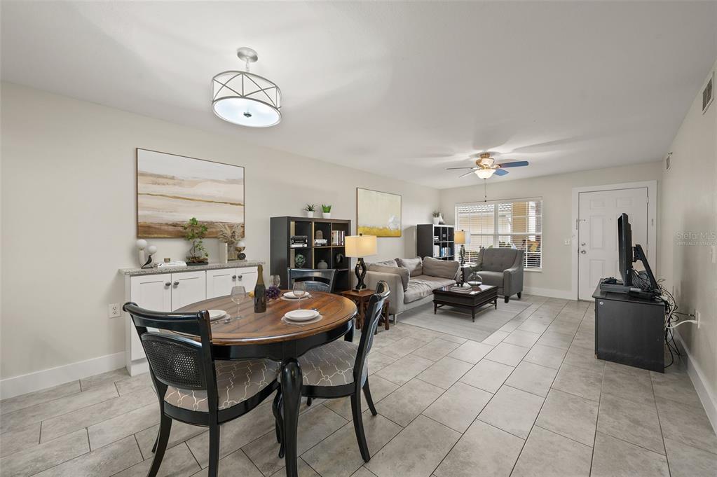 An open-concept living and dining area features tile flooring, neutral walls, and a ceiling fan — 4910 COUGAR COURT N UNIT 103, NAPLES, FL