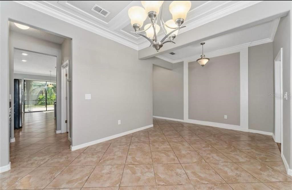 A dining room with tile flooring, a tray ceiling, and two hanging light fixtures — 12273 GREAT COMMISSION WAY, ORLANDO, FL