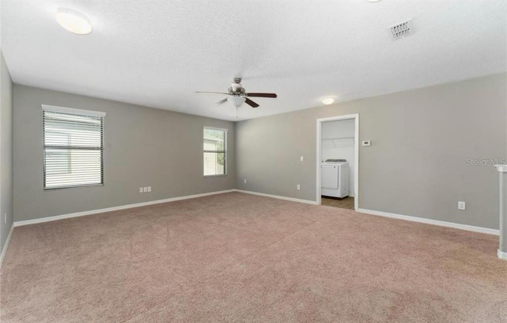 A spacious, carpeted room with light gray walls, a ceiling fan, and a laundry closet — 12273 GREAT COMMISSION WAY, ORLANDO, FL
