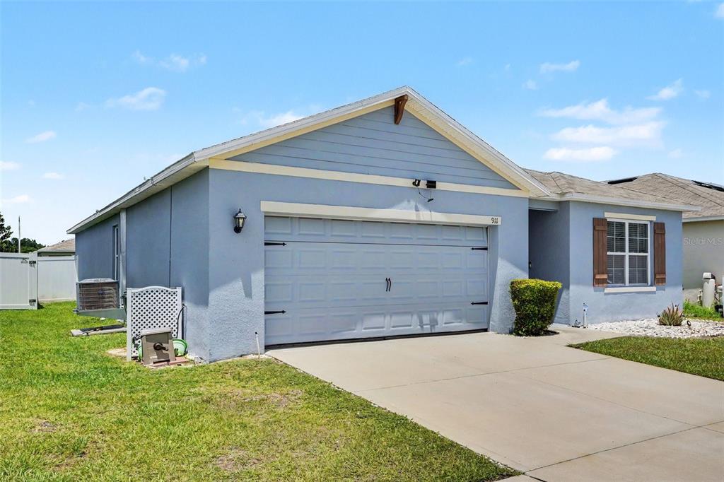 A light blue single-story house with a two-car garage and a concrete driveway — 911 WATERVILLE DR, AUBURNDALE, FL