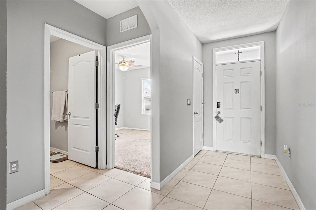 A tiled entryway leads to a carpeted room and a white front door with a transom — 911 WATERVILLE DR, AUBURNDALE, FL