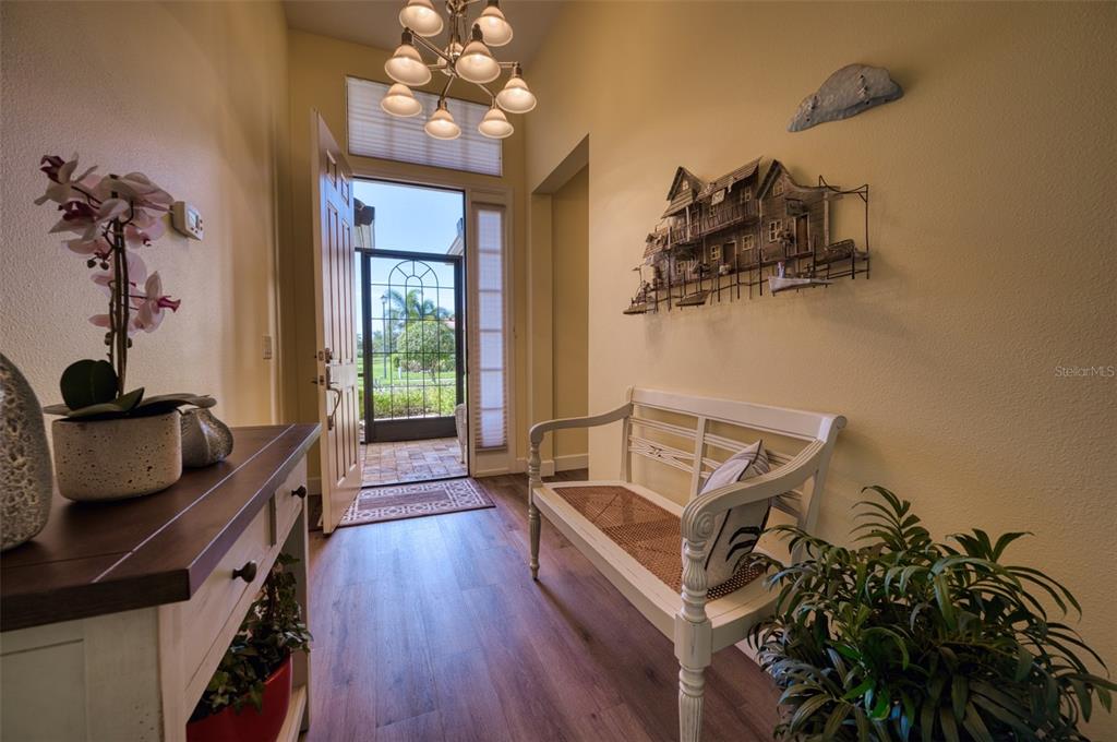 An entryway features a white bench, a console table with a plant, and an open door — 8053 STIRLING FALLS CIRCLE, SARASOTA, FL