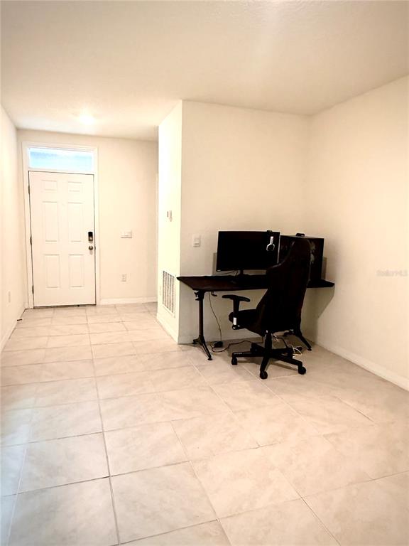 A room with light-colored tile flooring features a desk setup against a white wall — 2255 TAY WES DRIVE, ST CLOUD, FL