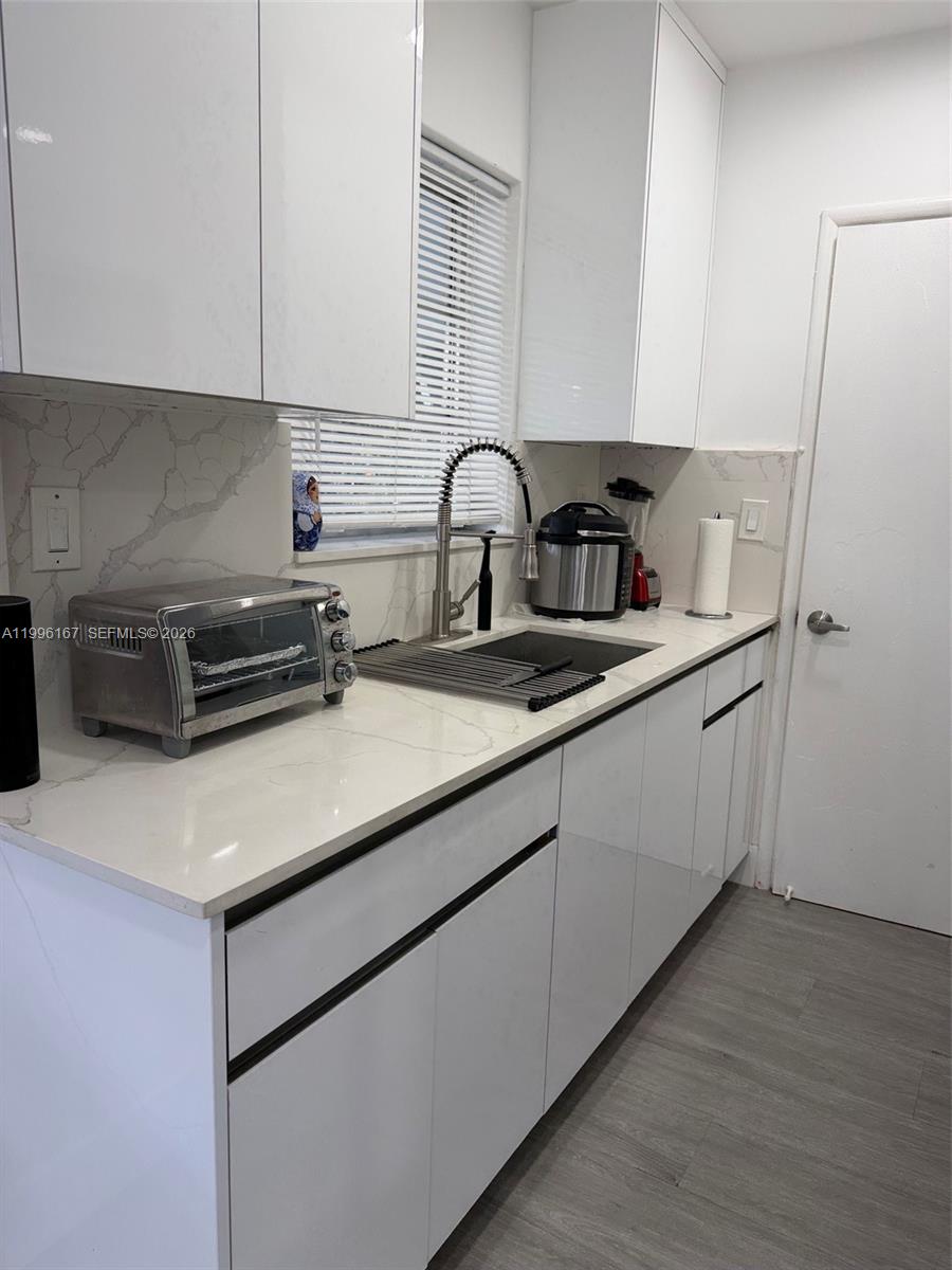 A modern kitchen features white glossy cabinets, a quartz countertop, and a stainless steel sink — 821 NE 6th St # 2, Hallandale Beach FL 33009, HALLANDALE BEACH, FL