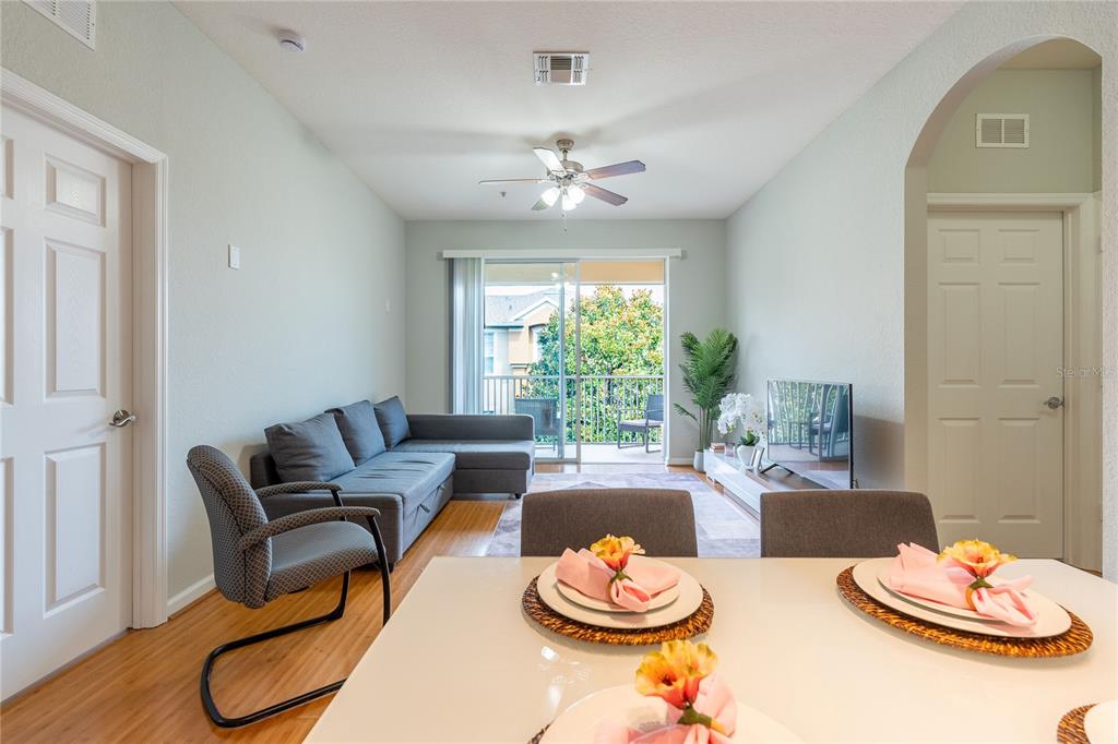 A dining area in the foreground opens into a living room with a sectional sofa — 2484 SAN TECLA STREET UNIT 408, ORLANDO, FL