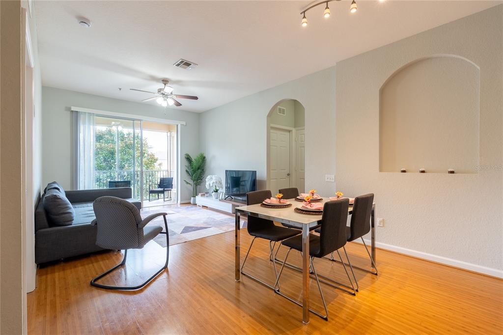 A living and dining area features hardwood floors, a sliding glass door, and an arched niche — 2484 SAN TECLA STREET UNIT 408, ORLANDO, FL