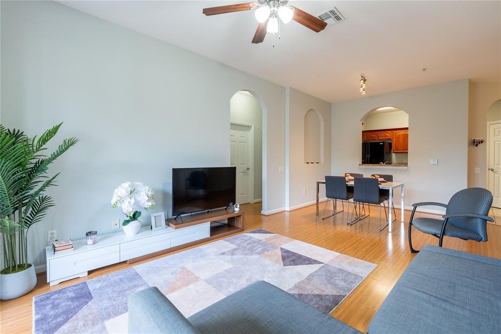A living room and dining area with hardwood floors, a ceiling fan, and arched doorways — 2484 SAN TECLA STREET UNIT 408, ORLANDO, FL
