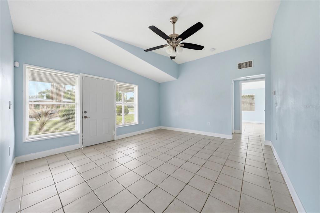 A room with light blue walls, a vaulted ceiling, a ceiling fan, and tiled flooring — 1311 HILLCREST DRIVE, DAYTONA BEACH, FL