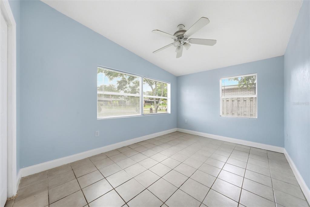 An empty room with light blue walls, white trim, tile flooring, and a ceiling fan — 1311 HILLCREST DRIVE, DAYTONA BEACH, FL