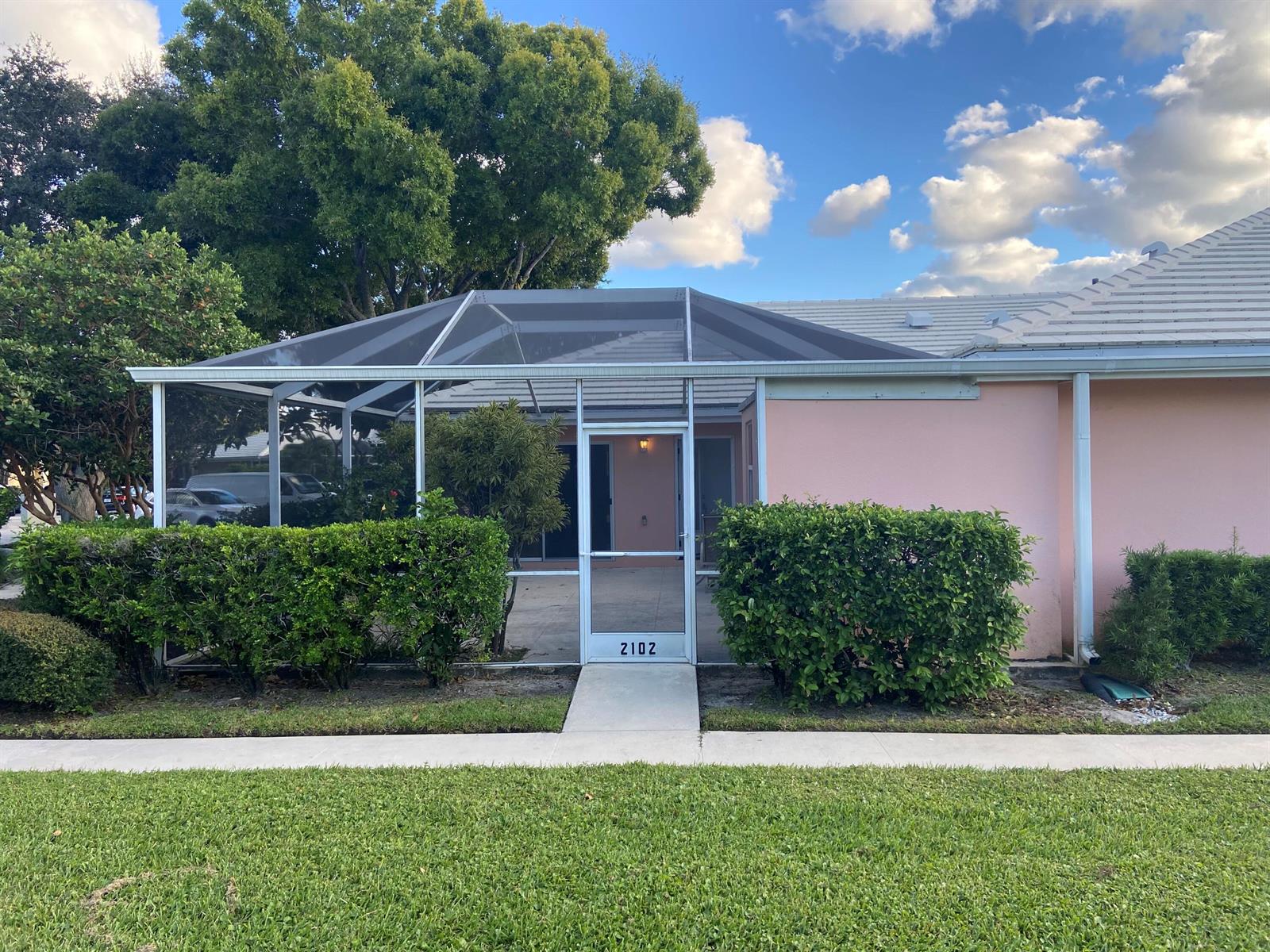 A pink house exterior features a screened-in patio entrance with a numbered door — 2102 Appleton Court, Palm Beach Gardens FL 33403, PALM BEACH GARDENS, FL