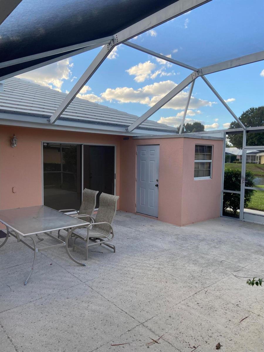 A patio with a screened enclosure, a table with chairs, and a light-colored exterior wall — 2102 Appleton Court, Palm Beach Gardens FL 33403, PALM BEACH GARDENS, FL