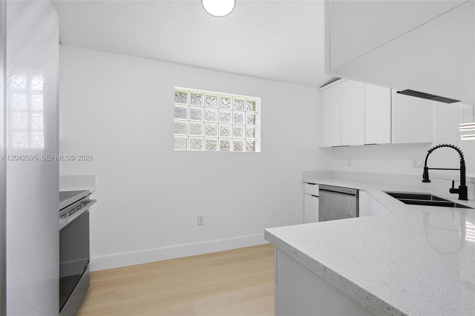 A bright kitchen features white cabinets, light wood flooring, and a glass block window — 4114 Sapphire St, Weston FL 33331, WESTON, FL