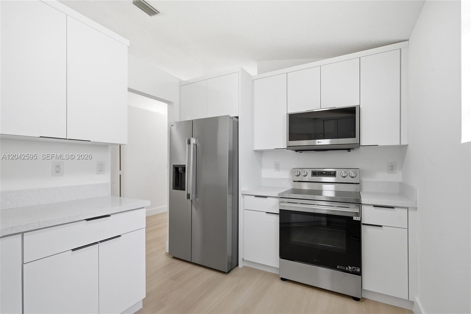 A modern kitchen features white cabinets, stainless steel appliances, and light-colored countertops — 4114 Sapphire St, Weston FL 33331, WESTON, FL