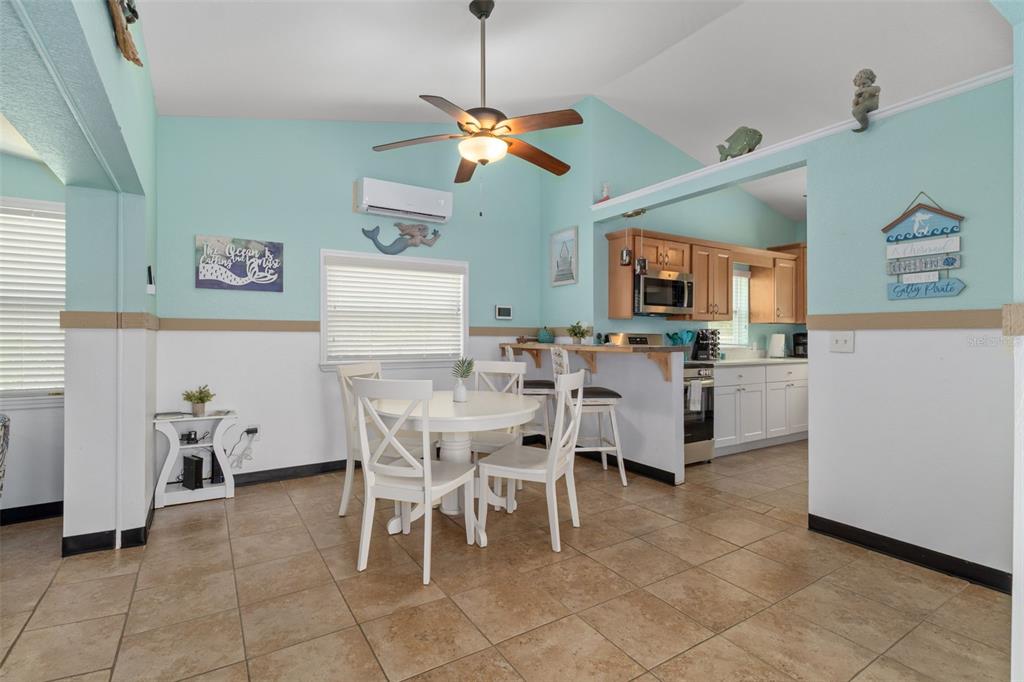 A dining area with a white table and chairs sits adjacent to a kitchen — 6245 WAVERLY ROAD, WEEKI WACHEE, FL