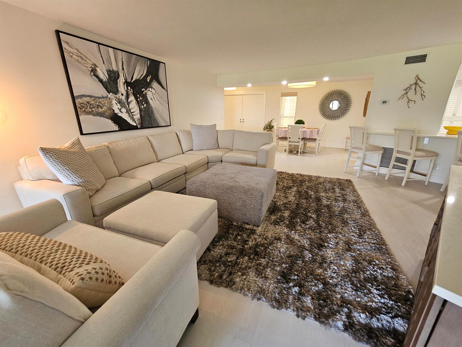 A living room features a large sectional sofa, a textured rug, and an adjacent dining area — 1357 NE Ocean # 104, Stuart FL 34996, STUART, FL