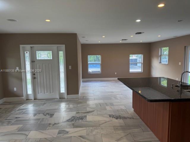 An open-concept room features light-colored tile flooring, recessed lighting, and a dark granite kitchen island — 200 NE 44th St # 0, Miami FL 33137, MIAMI, FL