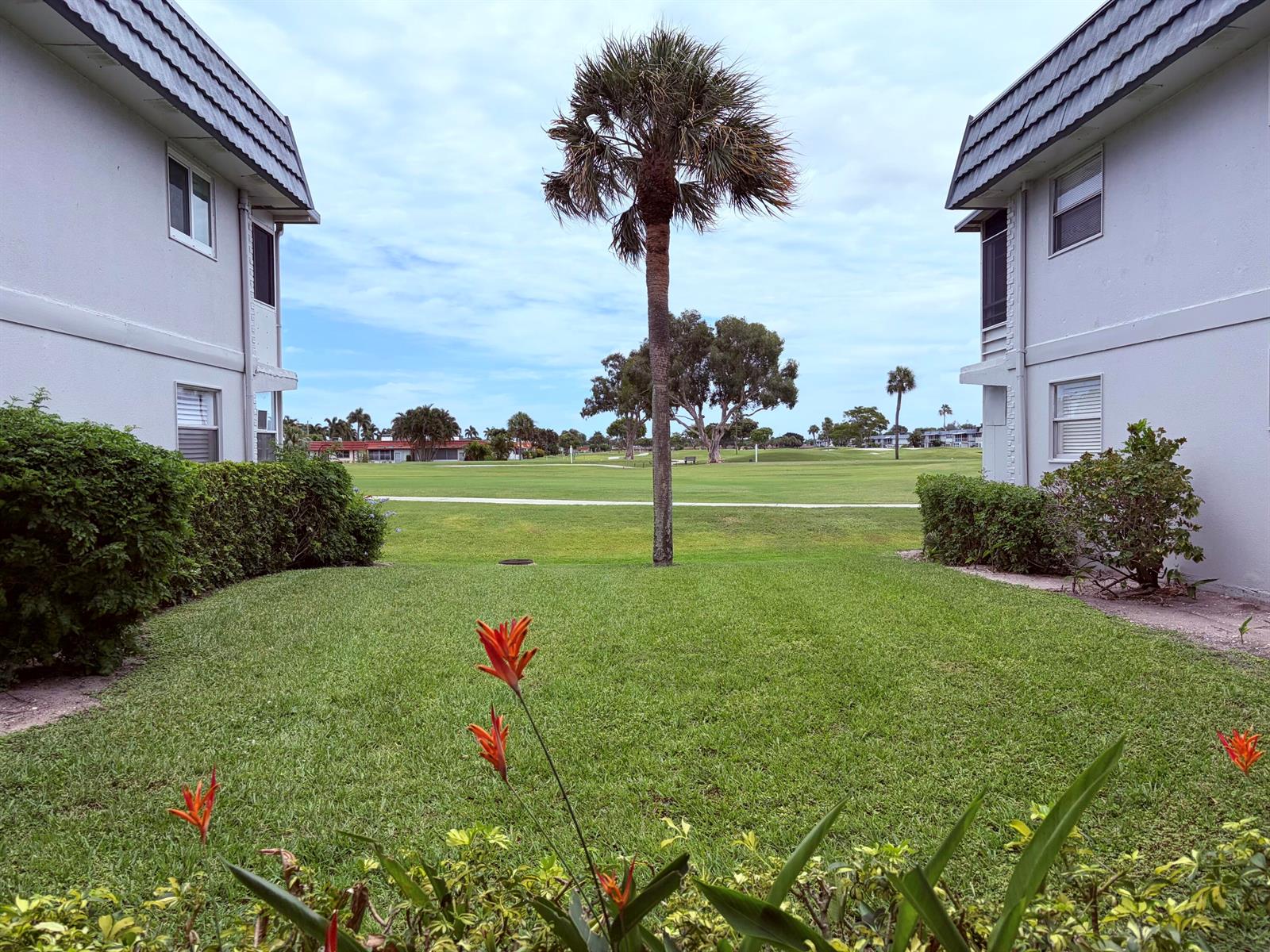 A view between two apartment buildings looking out over a green lawn and golf course — 207 Tuscany D # 207, Delray Beach FL 33446, DELRAY BEACH, FL