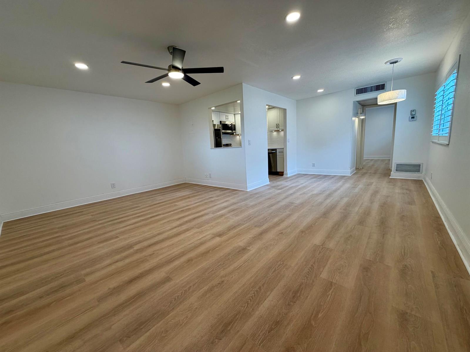 An open-concept living area features light wood-look flooring, white walls, and a ceiling fan — 207 Tuscany D # 207, Delray Beach FL 33446, DELRAY BEACH, FL