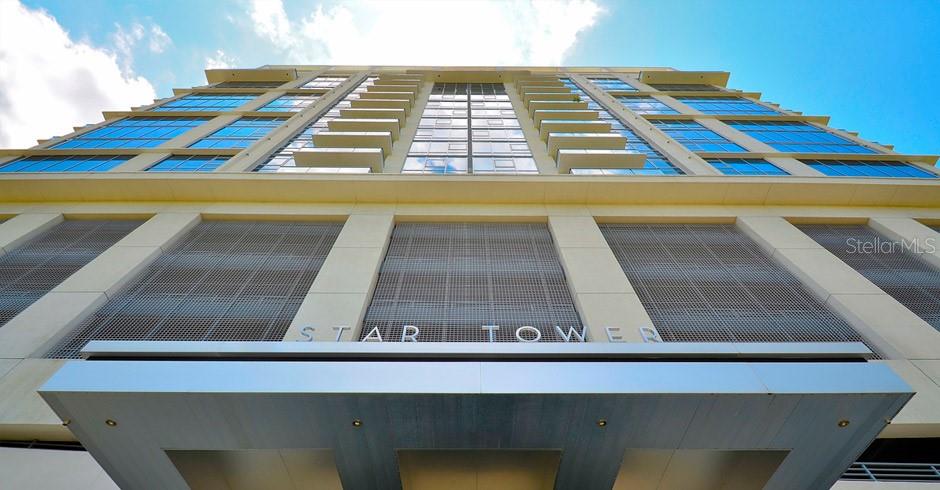 A low-angle exterior view of the Star Tower building featuring a prominent metal entrance canopy — 260 S OSCEOLA AVENUE UNIT 1102, ORLANDO, FL