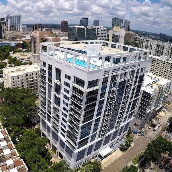 An aerial view of a modern white high-rise building featuring a rooftop swimming pool — 260 S OSCEOLA AVENUE UNIT 1102, ORLANDO, FL