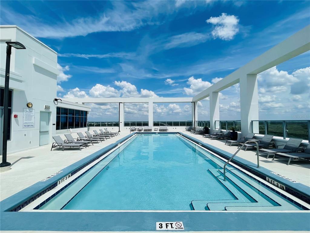 A rooftop swimming pool features lounge chairs on a deck under a bright blue sky — 260 S OSCEOLA AVENUE UNIT 1102, ORLANDO, FL