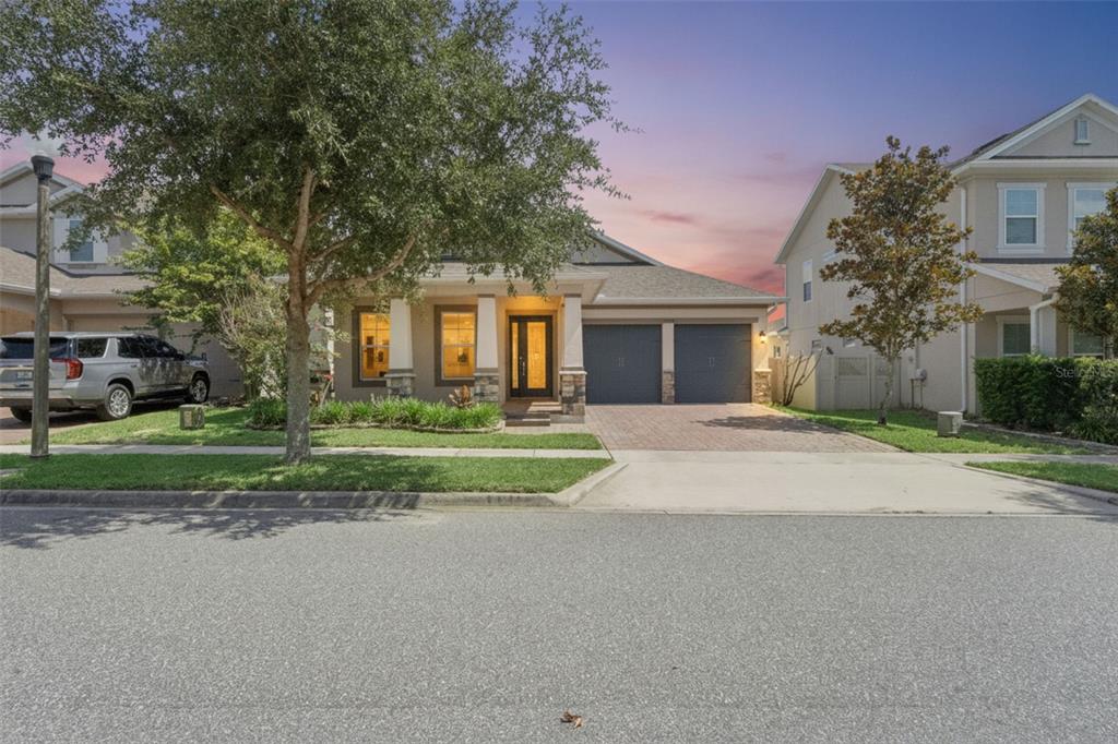 A single-story house with a two-car garage, stone accents, and a paved driveway — 15725 SWEET LIMETTA DRIVE, WINTER GARDEN, FL