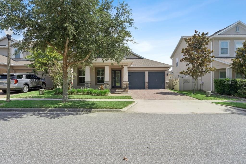 A single-story house with a two-car garage, stone accents, and a paved driveway — 15725 SWEET LIMETTA DRIVE, WINTER GARDEN, FL
