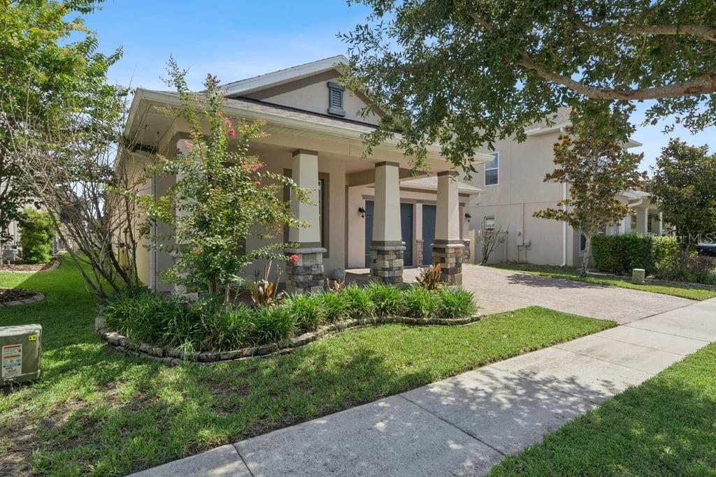 A single-story house with a stone-columned front porch and a paved driveway — 15725 SWEET LIMETTA DRIVE, WINTER GARDEN, FL