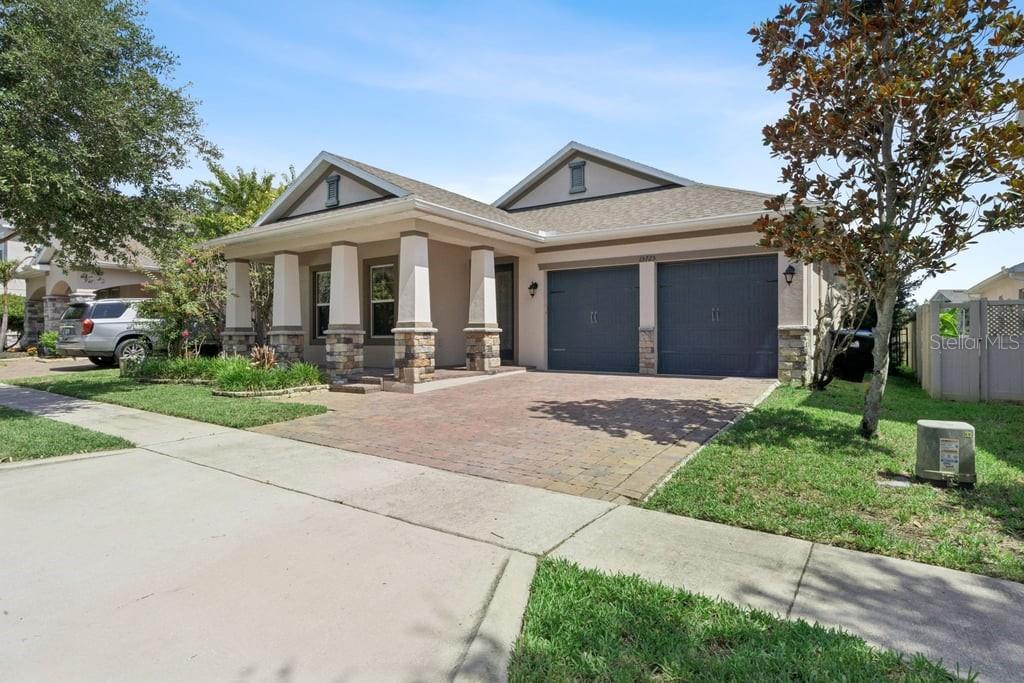 A single-story house with a brick paver driveway, two-car garage, and a covered front porch — 15725 SWEET LIMETTA DRIVE, WINTER GARDEN, FL