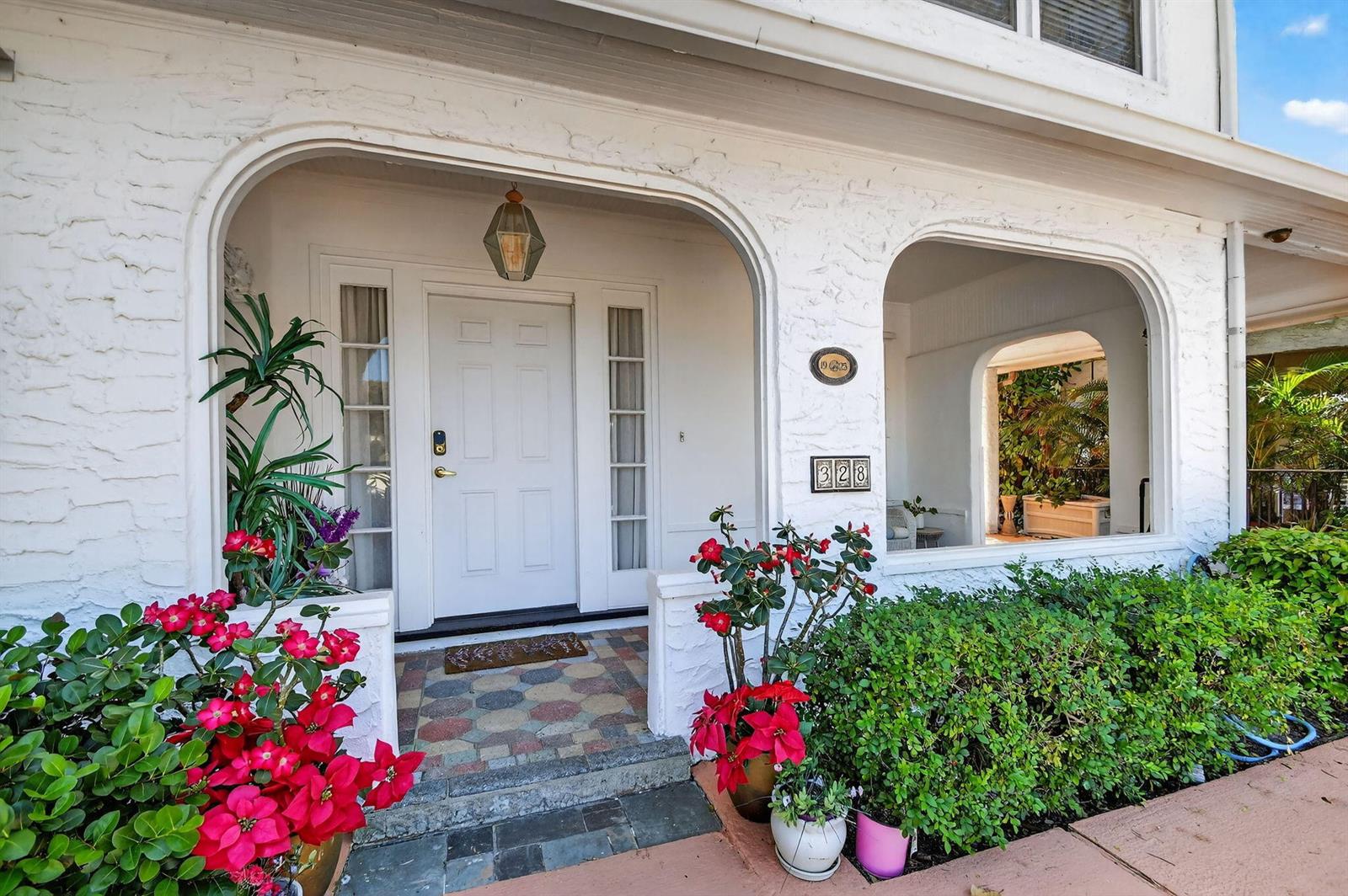 A white brick house exterior features an arched entryway, a front door, and potted plants — 328 Monroe Drive, West Palm Beach FL 33405, WEST PALM BEACH, FL