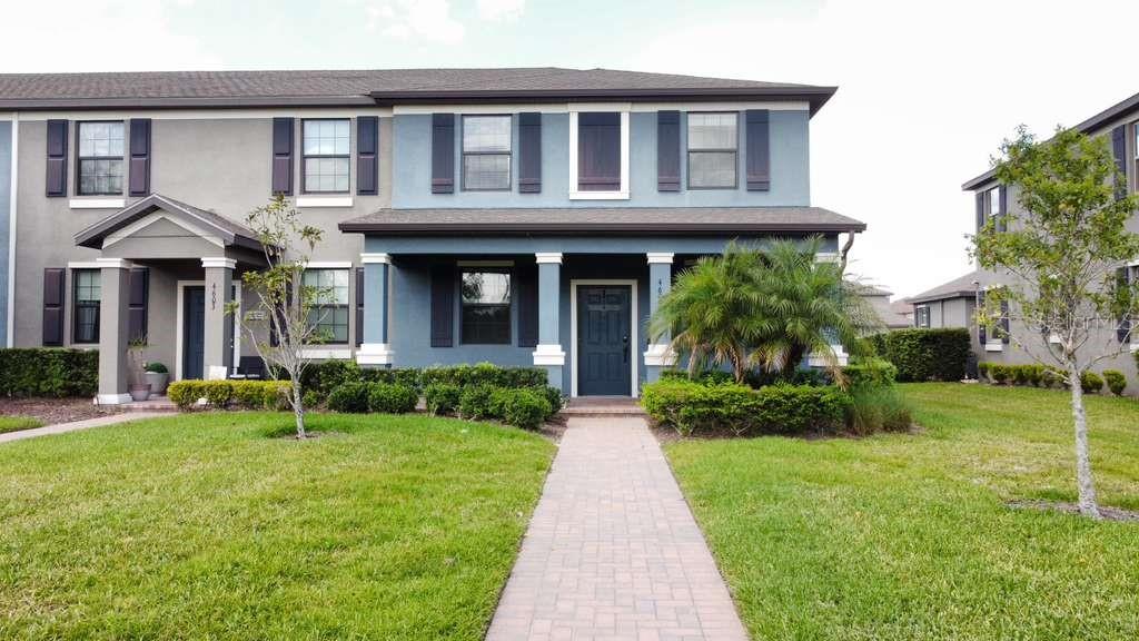 A two-story blue townhouse with a front porch, a paved walkway, and a grassy lawn — 4609 BEXLEY VILLAGE DRIVE, LAND O LAKES, FL