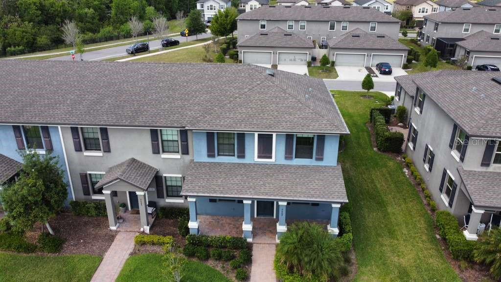 An aerial view shows the front exterior of a blue and gray multi-story townhouse — 4609 BEXLEY VILLAGE DRIVE, LAND O LAKES, FL